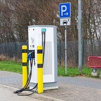 E-Auto-Ladestation mit passendem Parkschild im Hintergrund und gelb-schwarzen Rammschutzpfosten vor der Ladestation